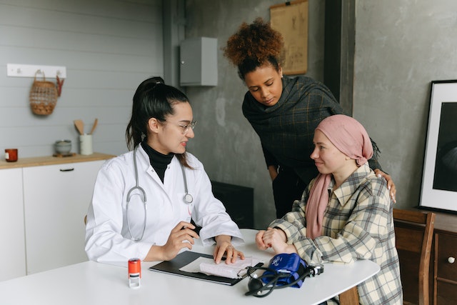 Photo of a woman with cancer at a doctor's appointment with a friend as an example of how to support your loved one going through cancer therapy.