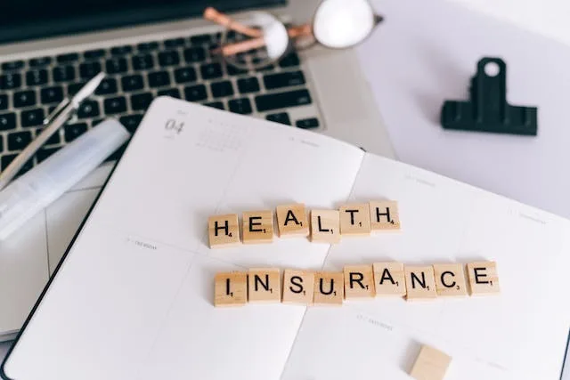 Paper and keyboard with letters that spell health insurance